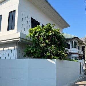 a white house with a tree on top of a white fence at House40 - MRT Ratchadaphisek in Bangkok