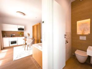 a bathroom with a sink and a toilet and a kitchen at M26 Prémium apartmanok in Tihany