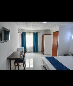 a bedroom with a desk and a bed and a table at HÔTEL MARIADOR PARK in Conakry