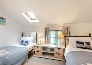 1 dormitorio con 2 camas, escritorio y ventana en White Rose Cottage, en Bodham