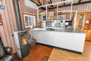 a kitchen with a stove in the middle of a room at Uniquely located wooden cottage by the sea - SJ1 in Harboør