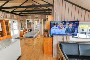 a living room with a flat screen tv on a wall at Uniquely located wooden cottage by the sea - SJ1 in Harboør