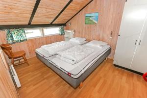 um quarto com uma cama num quarto com paredes de madeira em Uniquely located wooden cottage by the sea - SJ1 em Harboør