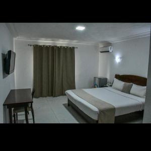 a bedroom with a bed and a table and a window at HÔTEL MARIADOR PARK in Conakry