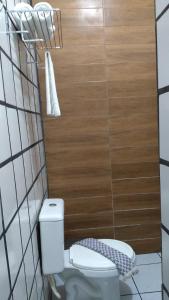 La salle de bains est pourvue de toilettes et d'un mur en bois. dans l'établissement Pousada Paraiso, à Santo Amaro