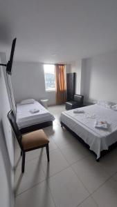 a bedroom with two beds and a chair and a window at EDIFICIO MALU REAL habitaciones y apartaestudios sin cocina in Popayan