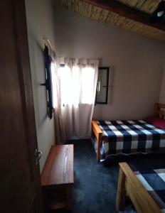 a room with two beds and a table and a window at CABAÑAS RIVIERA in Huacalera