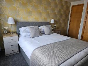 a bedroom with a large white bed with yellow wallpaper at 37 Farraline Court, City Centre apartment in Inverness