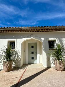 a white house with two potted plants in front of it at Villa Les Palmiers St. Maxime in Sainte-Maxime