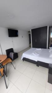 ポパヤンにあるEDIFICIO MALU REAL habitaciones y apartaestudios sin cocinaのベッドルーム1室(ベッド1台、テーブル、椅子付)