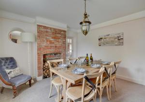 uma sala de jantar com uma mesa e cadeiras e uma lareira em Tusker House em Wells-next-the-Sea