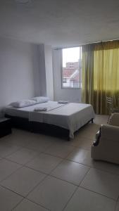 a bedroom with a bed and a window and a couch at EDIFICIO MALU REAL habitaciones y apartaestudios sin cocina in Popayan