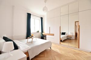 ein weißes Schlafzimmer mit einem Bett und einem Schreibtisch in der Unterkunft Warsaw City View Apartment - 63m2, Top Location, Workspace - by Rentujemy in Warschau