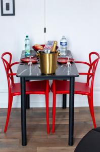 uma mesa preta com cadeiras vermelhas e um balde. em L'Hyper Centre - Netflix & Wifi - Lit Haut de Gamme & Sofa Tantra - check-in 24H24 - GoodMarning em Châlons-en-Champagne