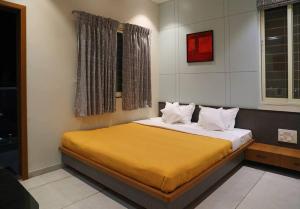 a bedroom with a bed with yellow sheets and a window at 'Sumadhu Homes - 201 ' in Kolhapur