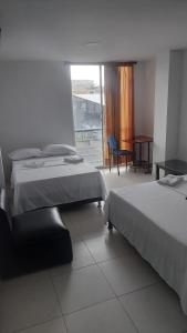 a bedroom with two beds and a table and a chair at EDIFICIO MALU REAL habitaciones y apartaestudios sin cocina in Popayan