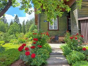 a house with red flowers in the front yard at Tūrisma mītne ZVIEDRI in Līgatne