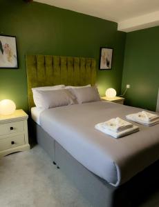 a bedroom with a large bed with green walls at Nomi Rooms & Restaurant in Bangor