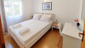 a small bedroom with a white bed and a desk at Apartments Martin in Drvenik