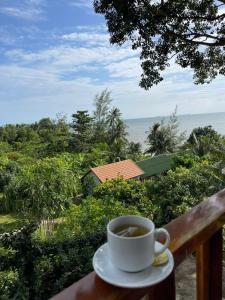 a cup of coffee sitting on a balcony overlooking the ocean at Cosiana Resort in Phú Quốc