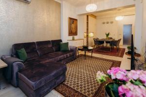 a living room with a brown leather couch and a table at Krum khan Top Centre Apartment in Sofia