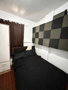 a bedroom with a black bed in a room at Semi Studio Room at EKG House Rental in Manila