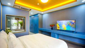 Hanoi Ben's Apartment and Hotel في هانوي: غرفة نوم بسرير ابيض وتلفزيون بشاشة مسطحة