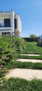 a walkway in front of a house with grass and flowers at Vila 29 Valamar in Durrës