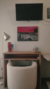escritorio con silla blanca y TV en la pared en Punto central Home in Heraklio city, en Heraclión