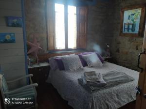 1 dormitorio con 1 cama, 1 silla y 1 ventana en La casuca de Antoniooti en Las Rozas de Valdearroyo