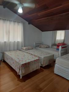 3 Betten in einem Zimmer mit weißen Wänden und Holzböden in der Unterkunft Pousada Recanto da Fé in Cachoeira Paulista