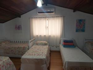 1 dormitorio con 2 camas individuales y ventana en Pousada Recanto da Fé, en Cachoeira Paulista