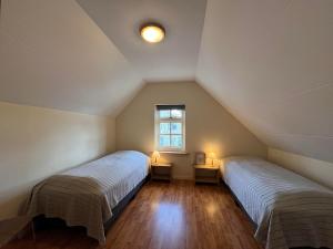 2 Betten in einem Dachzimmer mit Fenster in der Unterkunft It Winkelhûs in Terschelling