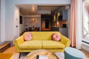 a living room with a yellow couch and pink pillows at Hotel Keur - Apartments in Zandvoort