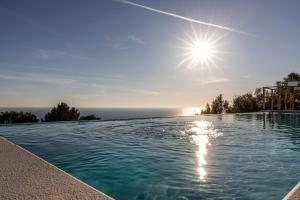 a swimming pool with the sun in the sky at Dimora Maiuri L'Olivella in Anacapri
