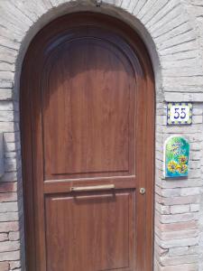 een houten deur in een bakstenen muur met een bord erop bij Casa vacanze Perfecta Laetitia Assisi in Tordandrea