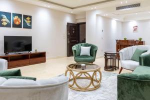 a living room with green chairs and a tv at El Lotus Building in Cairo