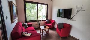 een woonkamer met twee rode stoelen en een televisie bij House on a Hill with Stunning Views near Troodos in Silikou