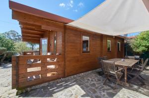 una cabina in legno con tavolo e sedie su un patio di Montargil Lakeside Bliss, by TimeCooler a Montargil