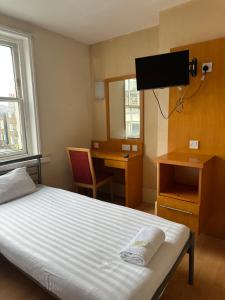 a bedroom with a bed and a desk and a television at Berkeley Court Hotel in London