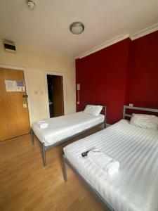 two beds in a room with a red wall at Berkeley Court Hotel in London