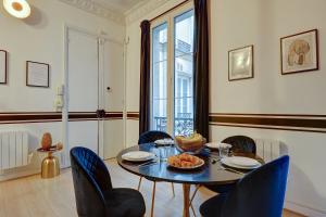 106 - Fabulous studio in Champs Elysees في باريس: غرفة طعام مع طاولة وكراسي زرقاء