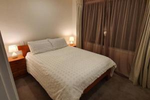 ein Schlafzimmer mit einem Bett mit zwei Lampen und einem Fenster in der Unterkunft Modern Two-Bedroom Home in Merivale in Christchurch