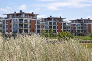 Deux grands immeubles d'appartements avec de l'herbe au premier plan dans l'établissement Duenenpark-Heiligenhafen-Haus-Ostseeduene-Wohnung-3-Beach-Apartment, à Heiligenhafen