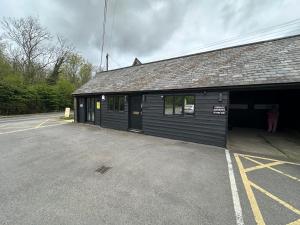 a black building with a parking lot in front of it at The Stables in Takeley