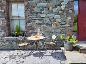 stół i krzesła na patio z kamienną ścianą w obiekcie Reeks Country House w Killarney