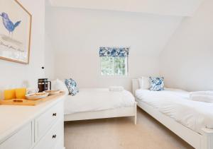 a white bedroom with two beds and a window at Cuckoo Lodge in Wighton