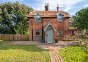 an old brick house with a green door at Cuckoo Lodge in Wighton