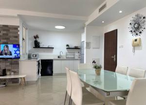 une salle à manger et une cuisine avec une table et des chaises en verre dans l'établissement TRENDY 2BR GOLF RESIDENCE EILAT, à Eilat