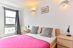 1 dormitorio con cama rosa y ventana en City Centre Apartments Shoreditch, en Londres
